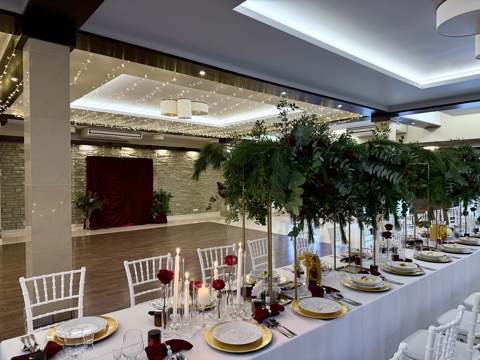Długi stół biesiadny z girlandą zieleni i czerwonych róż – Restauracja Stara Kuźnia w Kornatce koło Dobczyc